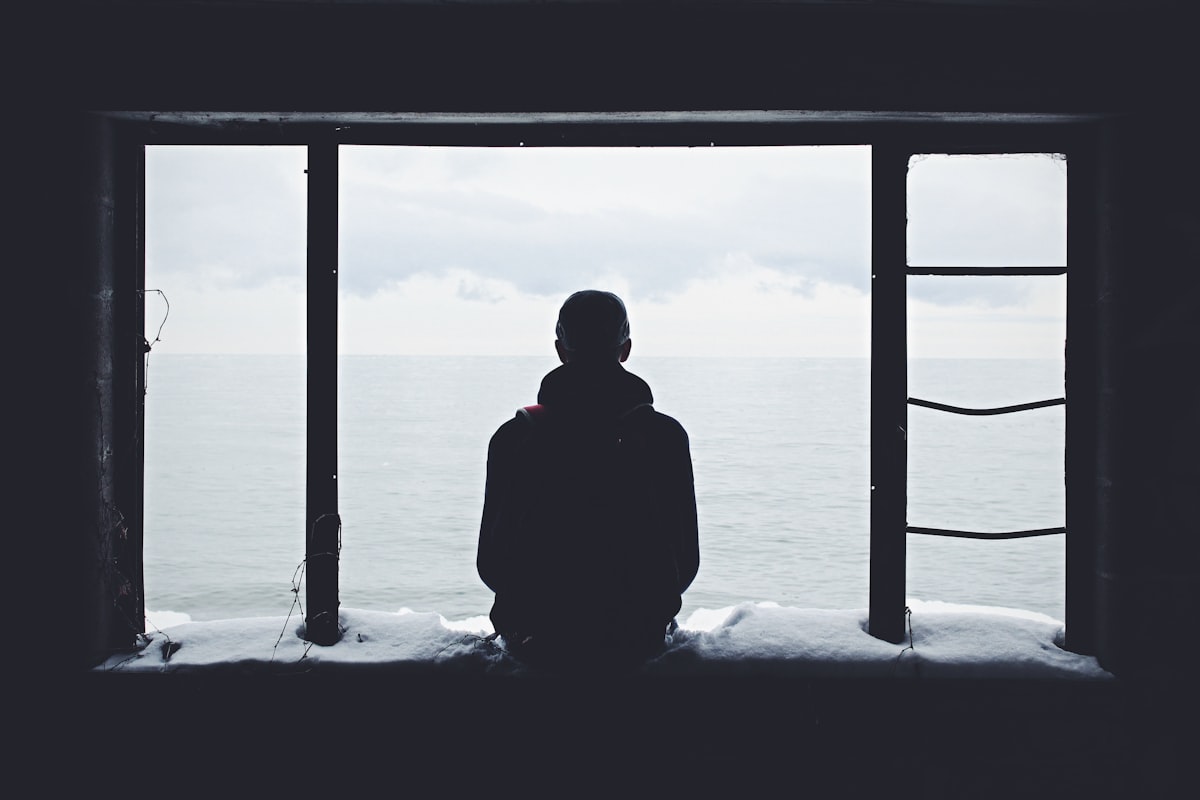 Person sitting alone looking down, illustrating the weight of depression