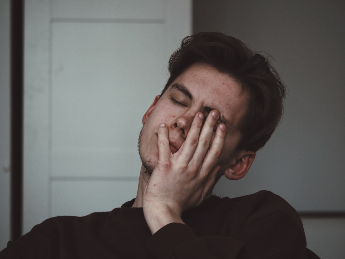 Person pressing hands to their temples in pain, illustrating a migraine headache