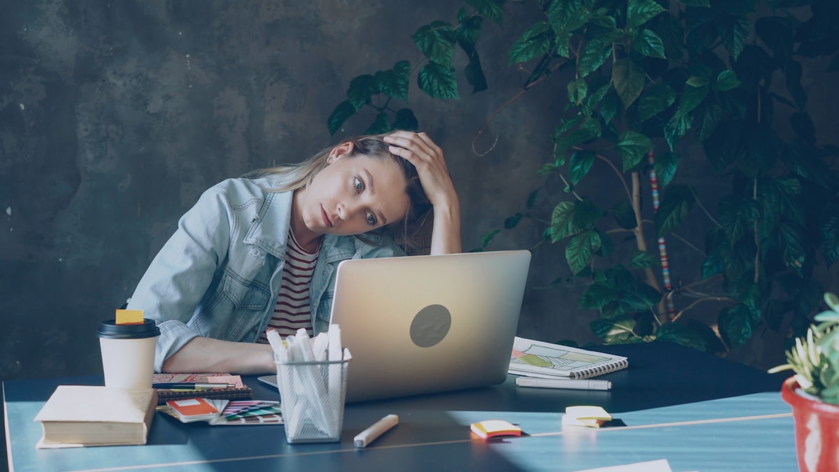 Overwhelmed person holding their head at a desk, illustrating chronic stress
