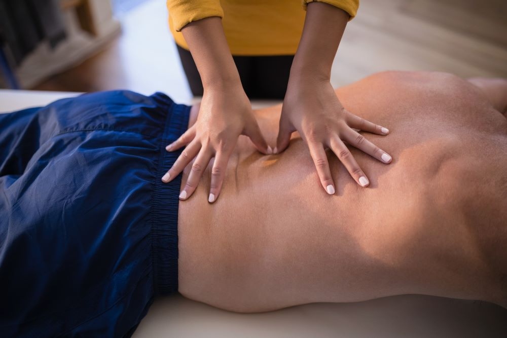 Therapist's hands applying deep, focused pressure to a client's lower back to relieve nerve tension