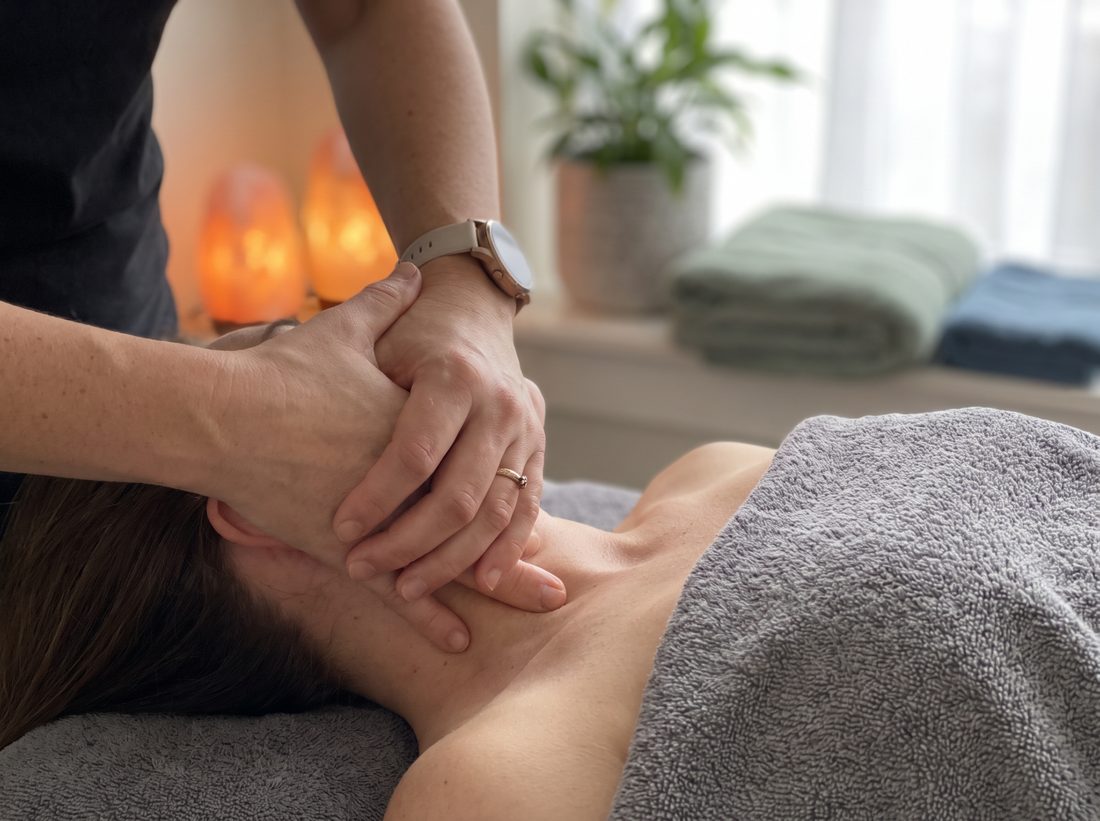 Close-up of a therapist's hands performing precise pressure-point therapy on a client's neck and shoulder